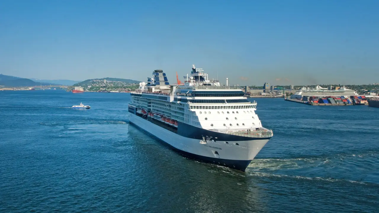 A large cruise ship sailing on open ocean under a clear blue sky.