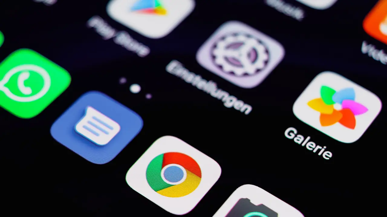 Nahaufnahme eines Handybildschirms voller App-Symbole vor dunklem Hintergrund.