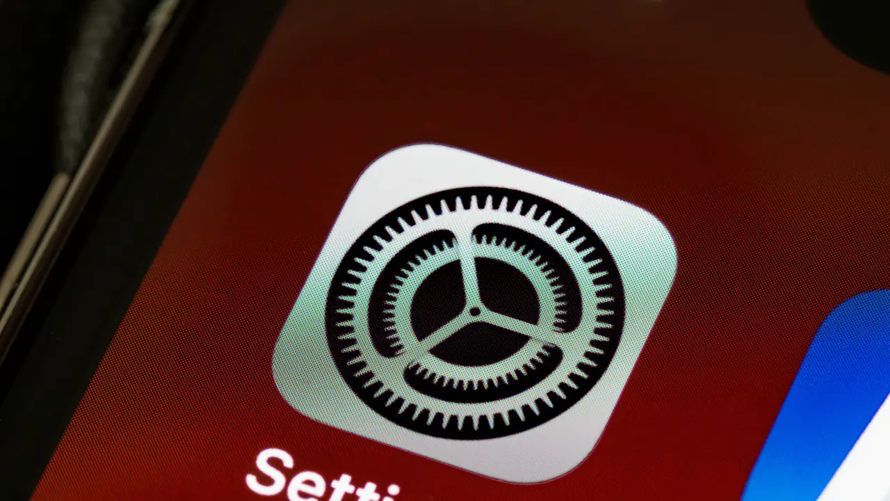Nahaufnahme eines iPhone-Bildschirms, auf dem das graue Zahnrad-Symbol der Einstellungen-App zu sehen ist.