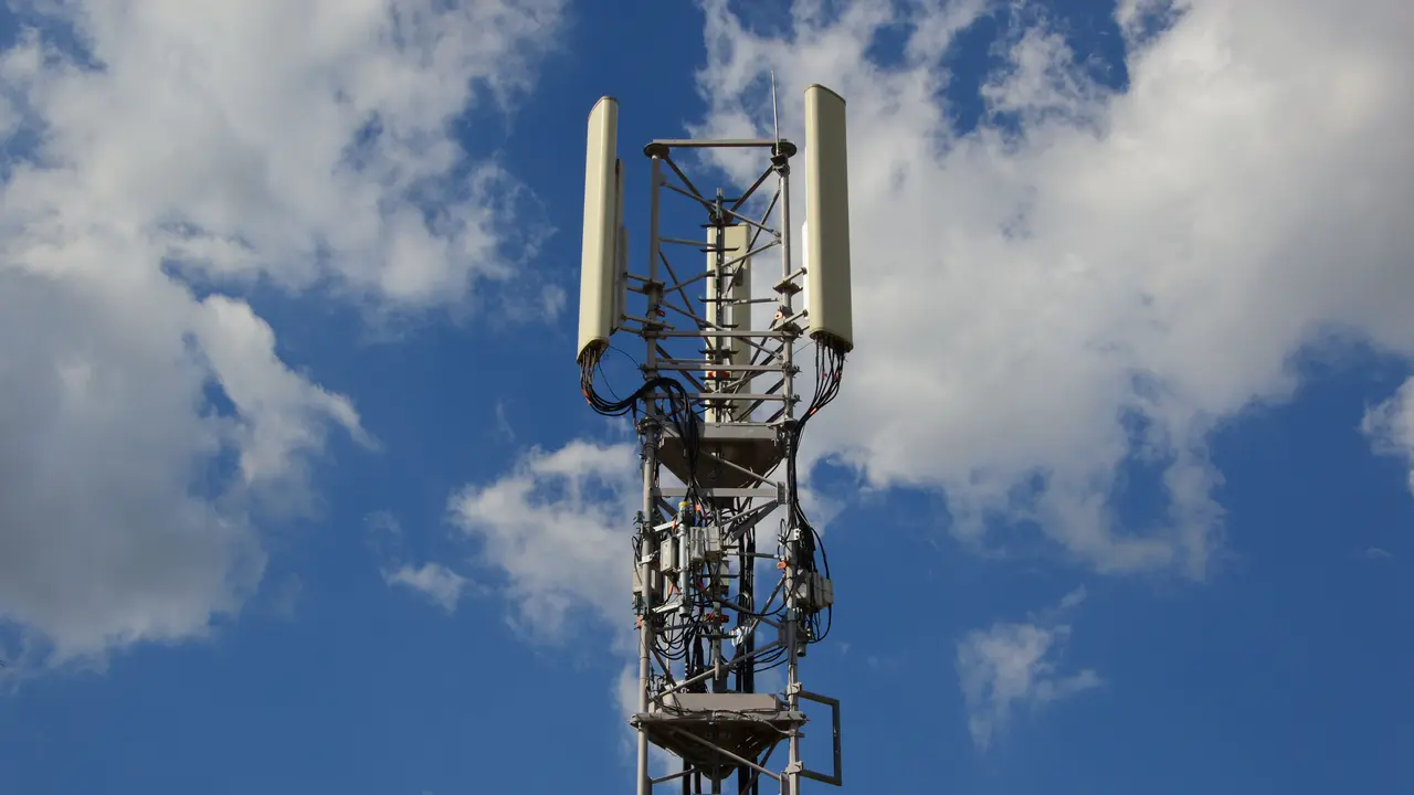 Un’antenna per la telefonia mobile che si staglia contro un cielo azzurro senza nuvole.