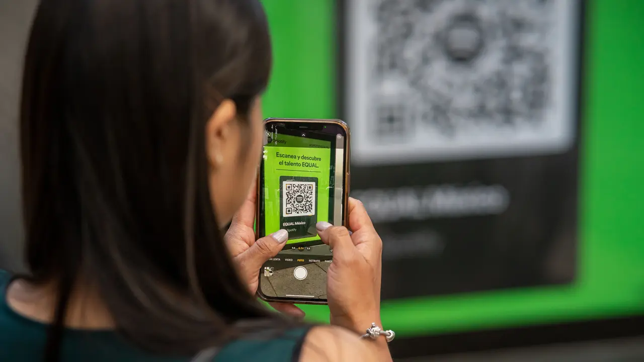 Une femme scanne un QR code avec son téléphone, dans une rue de Mexico.