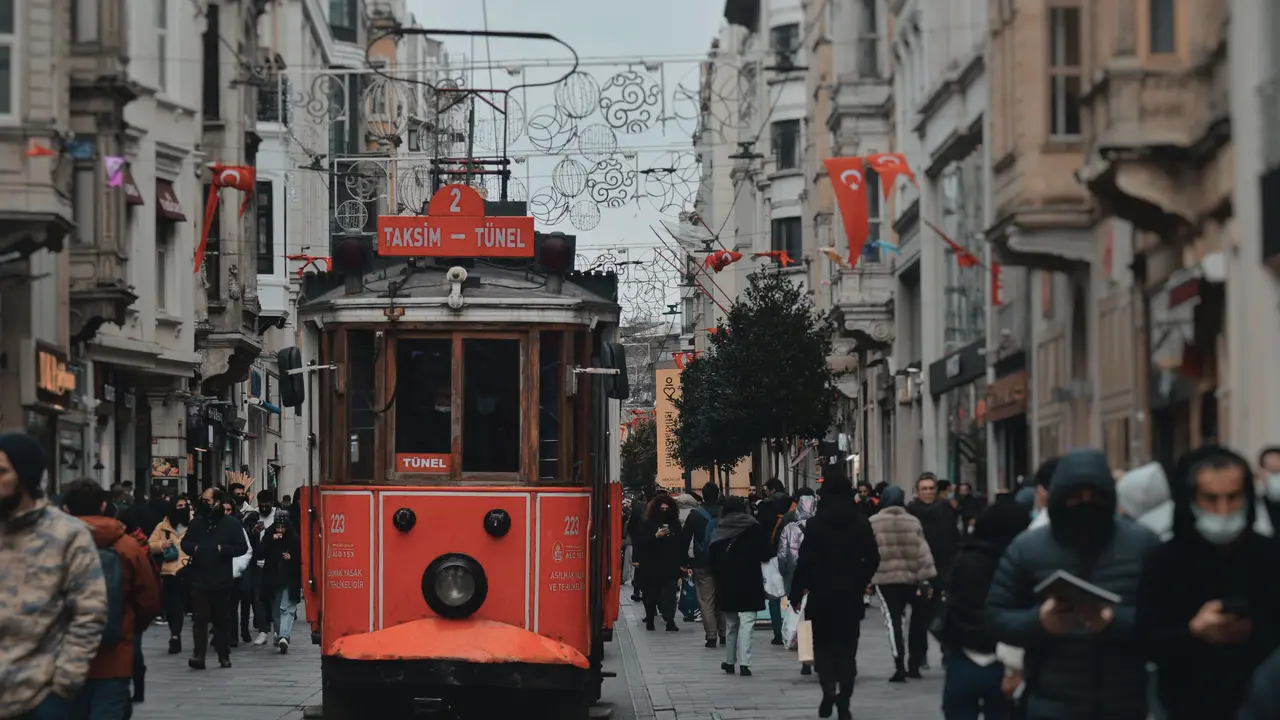 Eine rote Straßenbahn fährt durch eine belebte Fußgängerstraße in Istanbul.