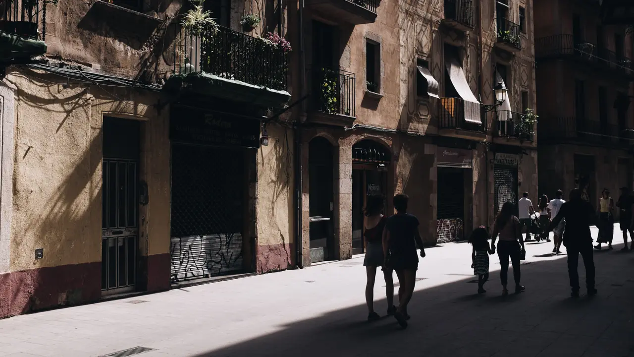 Eine belebte Straße in Barcelona zwischen historischen Häuserzeilen.