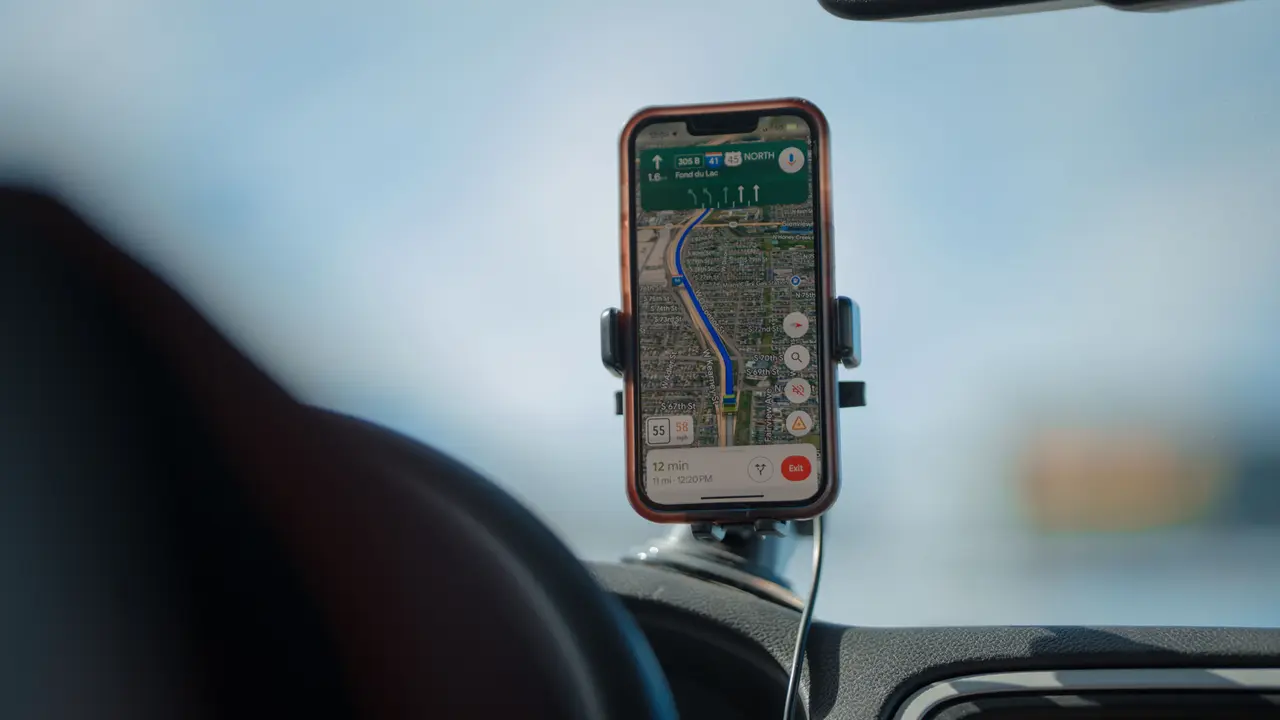 Un móvil con una app de navegación en marcha, sujeto en el salpicadero de un coche.