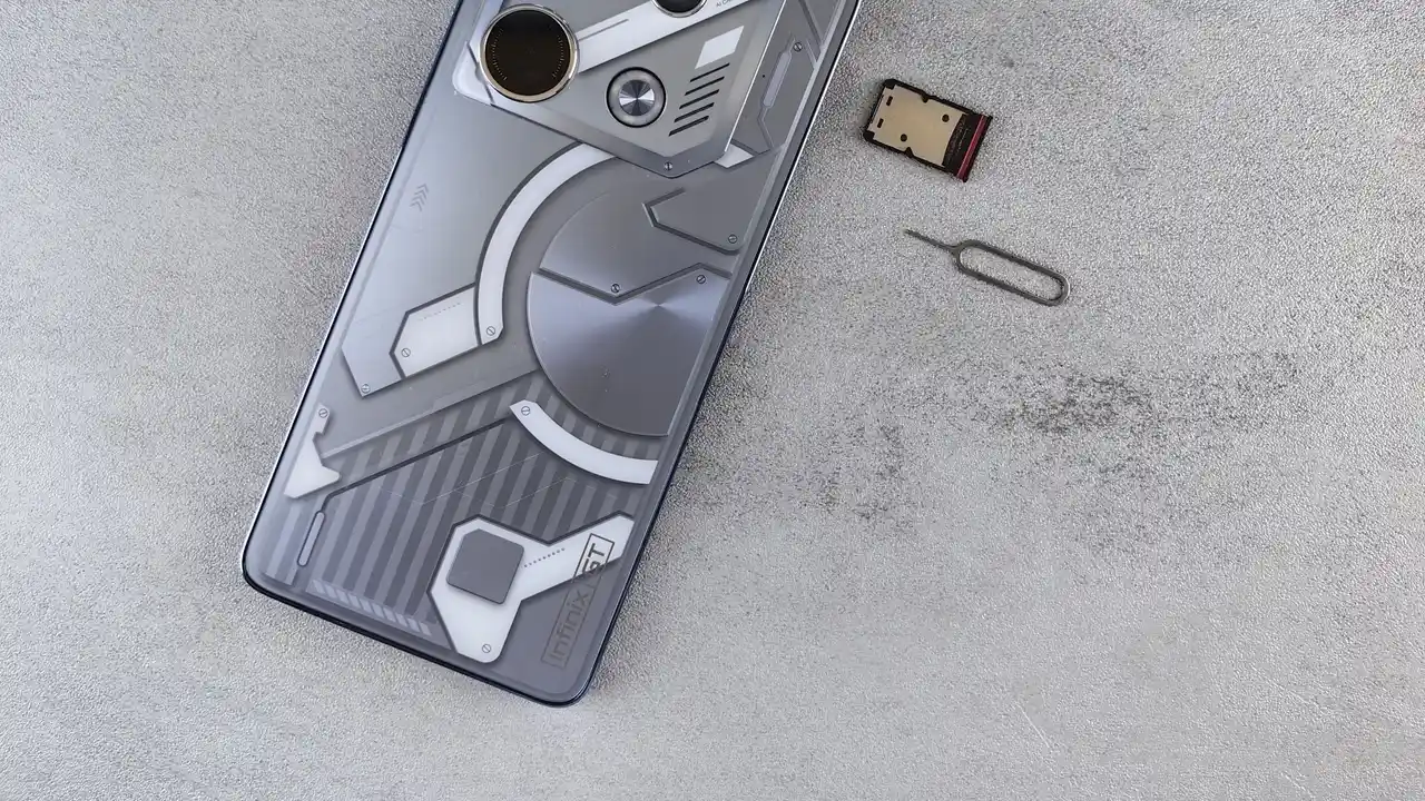 Gri bir yüzeyde duran telefon, yanında bir SIM kart ve SIM çıkarma iğnesi.